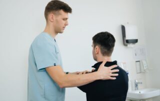 Physiotherapist examining a patient's shoulder in a clinical setting for rotator cuff assessment.