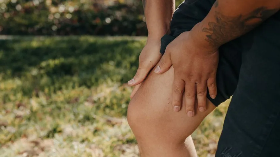 Person clutching painful knee outdoors, illustrating knee pain from spring yard work in Treasure Valley.