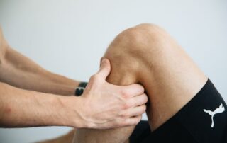 Close-up of a physiotherapist performing knee massage treatment to address knee pain from summer activities