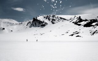 Skier carving down a groomed run on a snowy mountain under blue sky